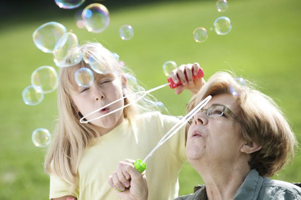 A little girl blowing bubbles with her grandmother.